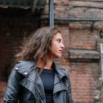 Brick Building - Woman in a Leather Jacket Looking Sideways