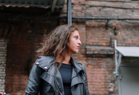 Brick Building - Woman in a Leather Jacket Looking Sideways
