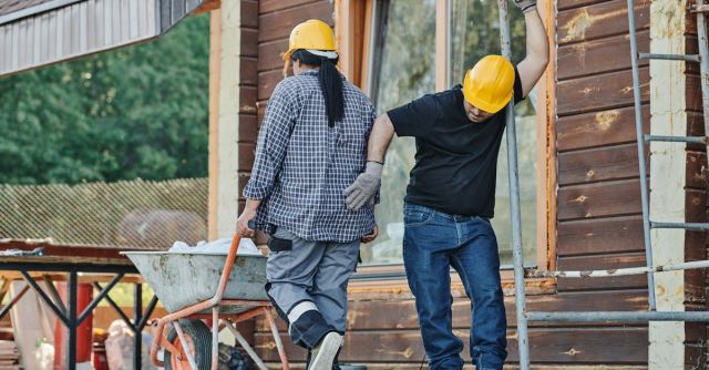 Construction Workers - Man in Black Shirt and Blue Denim Jeans Standing beside Scaffolding