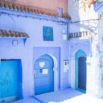 Masonry Wall - Blue exterior of house with doors located under sunlight on street with green plants in city of Morocco in summer