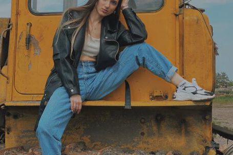 Bulldozer - Woman in Black Leather Jacket and Blue Denim Jeans Sitting on Yellow Bulldozer