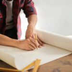 Builder - Male constructor drawing draft on paper roll