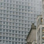 Skyscraper Construction - Low angle of modern multistage building exteriors with geometric windows on front walls in misty weather in town