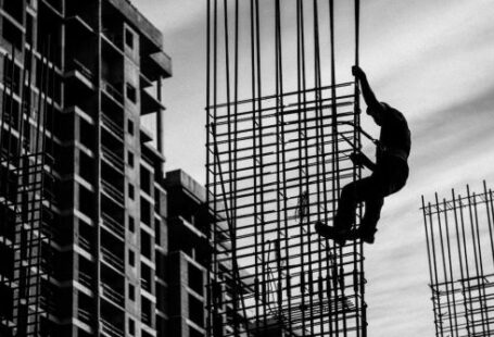 Construction Workers - Silhouette of Man Holding onto Metal Frame