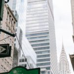 Skyscraper Construction - From below of crossroad signpost with traffic light located on street with modern skyscrapers in downtown of New York city
