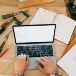 Construction - A Person Using a Laptop While on the Carpentry Workbench