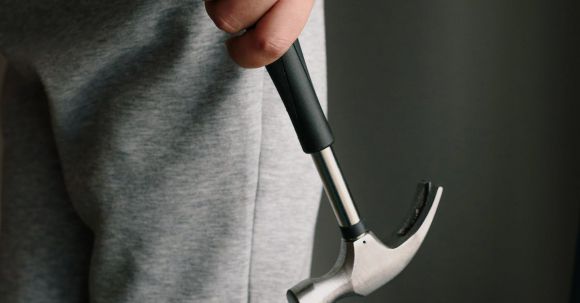 Construction Tools - Crop unrecognizable male in casual clothes holding metal hammer with rubber handle in room