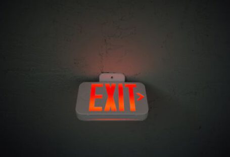 Construction Industry - From below of illuminated exit sign hanging on gray concrete ceiling in dark room