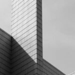 Skyscraper Construction - From below black and white of contemporary geometric construction exterior with tall walls under light cloudy sky in sunny day