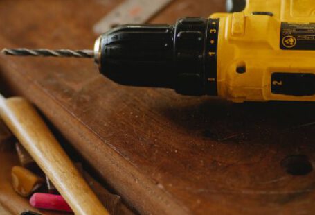 Construction Industry - From above of contemporary screwdriver with drill near hammer and tools on wooden desk
