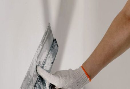 Concrete Trowels - Crop anonymous male worker in gloves holding putty knife while working at home