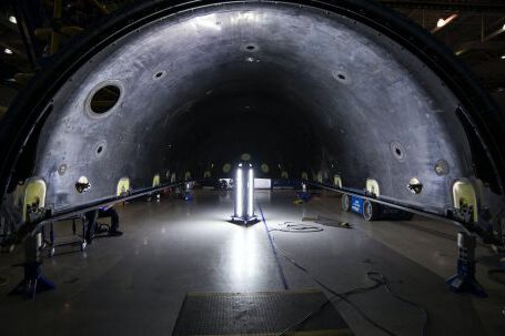 Heavy Construction Equipment - Illuminated tunnel with rocket construction equipment and lights in dark contemporary spacious industrial factory