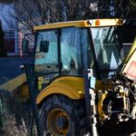 Excavator - Yellow and Black Backhoe Near the Wire Fence