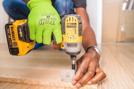 Construction - Person Using Dewalt Cordless Impact Driver on Brown Board