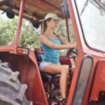 Heavy Construction Equipment - Woman in Blue Tank Top Driving a Red Tractor