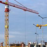 Heavy Construction Equipment - Three Yellow and Red Tower Cranes Under Clear Blue Sky