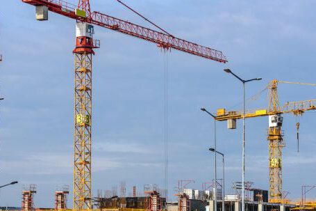 Heavy Construction Equipment - Three Yellow and Red Tower Cranes Under Clear Blue Sky