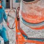 Concrete Mixers - Construction Worker Standing Beside A Concrete Mixer