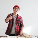 Builder - Laughing male constructor showing thumb up at working desk