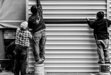 Construction Workers - Grayscale Photo of Three Men Arranging Metal Wall